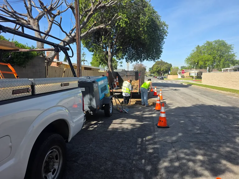 Right-of-way utility work in progress with an Ambros field crew, work truck, and traffic cones