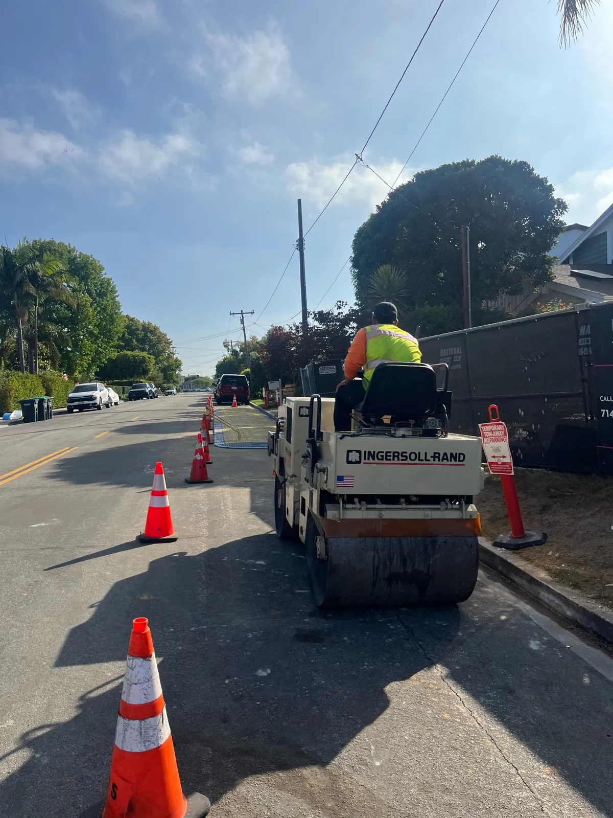 Street work zone and paving equipment during completed underground utility connection work in Newport Beach